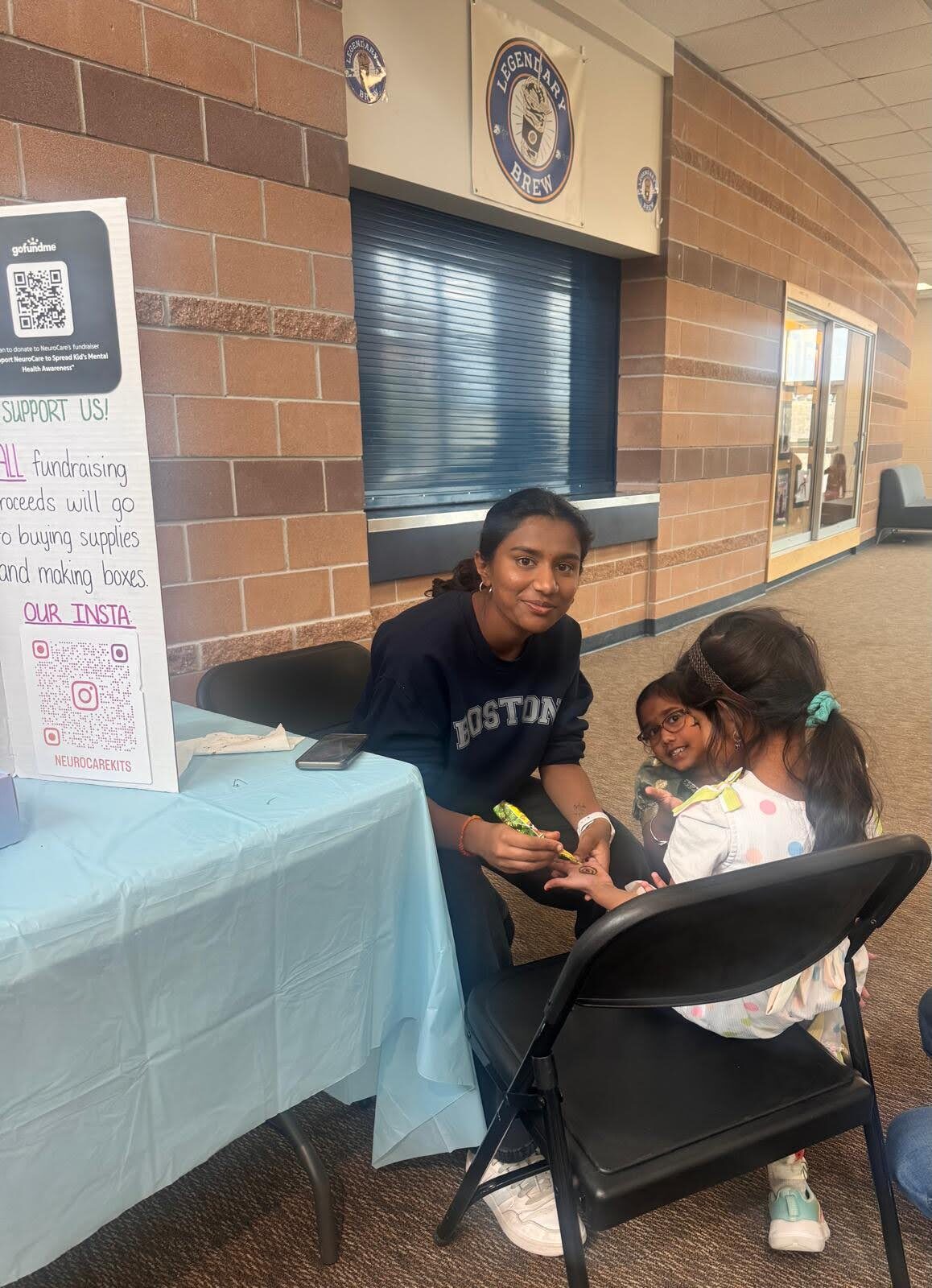 Volunteer painting henna for a young supporter at the fundraiser